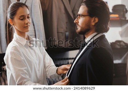 Banner luxury atelier classic menswear, Professional dressmaker taking measurements of businessman. Tailor fitting bespoke suit to handsome man.