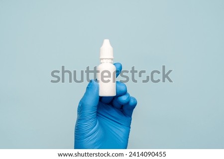 A plastic small bottle in doctors hand. Eye, ear or nose drops
