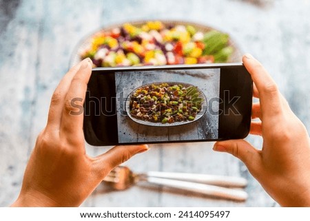 Girl taking picture of quinoa salad with smartphone- close-up