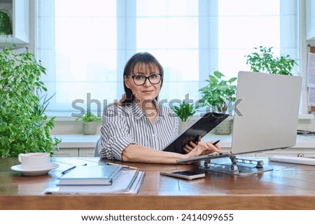 Portrait of mature woman working at home on computer laptop Royalty-Free Stock Photo #2414099655