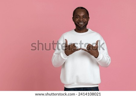 Black man wearing white sweatshirt using sign language Royalty-Free Stock Photo #2414108021