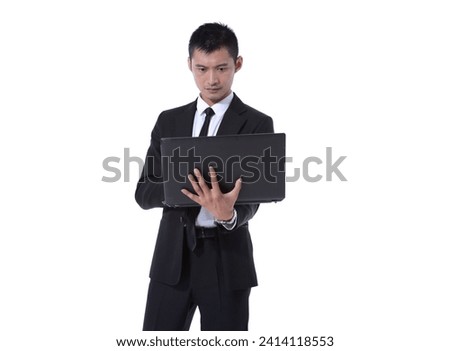 portrait of young business man in wearing black suit using laptop posing studio