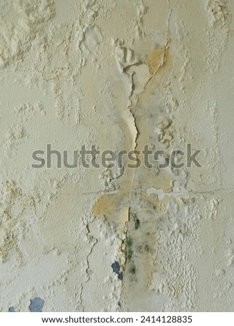 Badly fixed building facade wall covered with cracks in paint. Missing patch of paint in the middle; crack with flappy peeling edges. vintage background Royalty-Free Stock Photo #2414128835