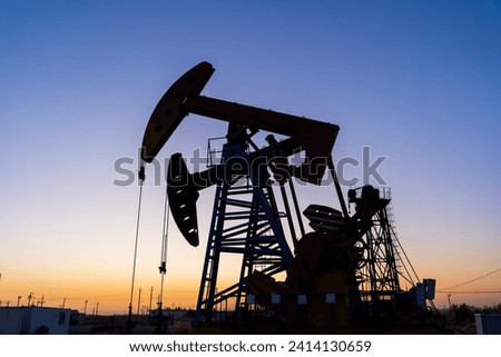 Oil field site, in the evening, oil pumps are running, Silhouette of beam pumping unit
