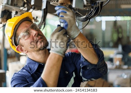 Senior professional electrical or industrial engineer inspecting and repairing a robotic system in the manufacturing factory close up. Robotic technician repairing - fixing a automated machine. Royalty-Free Stock Photo #2414134183