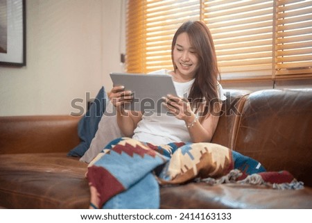 Smiling young woman using computer tablet, sitting on couch