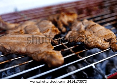 Grilling steaks on charcoal Barbecue grill outdoors in yard.