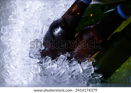 Bucket with bottles of beer and ice cubes, top view. Cubes of ice and colorful bottles with cold beer and drinks. Top view, close-up. Preparation for the festive event.