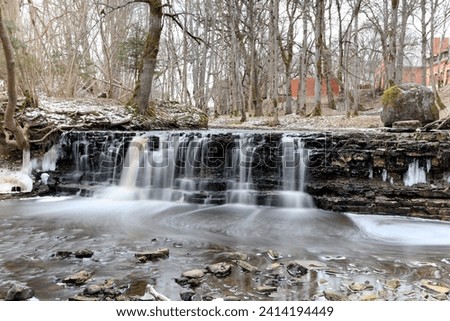 a small beautiful waterfall on a small river in winter
