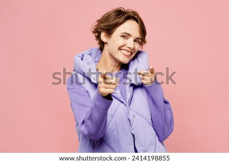 Young happy woman she wear purple vest sweatshirt casual clothes point index finger camera on you motivating encourage isolated on plain pastel light pink background studio portrait. Lifestyle concept