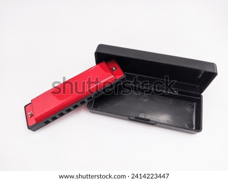 a red harmonica with a black box