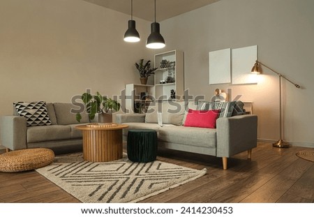 Interior of stylish living room with grey sofas and glowing lamps at evening Royalty-Free Stock Photo #2414230453