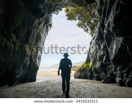 Man walking out of Muriwai cave. Muriwai Beach. Auckland.  Royalty-Free Stock Photo #2414233311