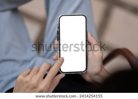 Close-up image of a man using his smartphone, touching on screen, scrolling on a website or social media while relaxing sitting outdoors. A smartphone mockup. People and technology concepts