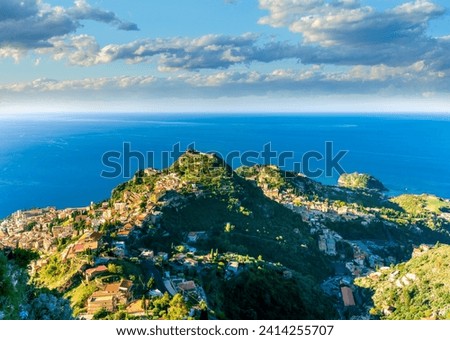 scenic view from highland to a mountain town with beautiful buildings, castles, hills and slopes and panoramic sea gulf with cloudy sky on background