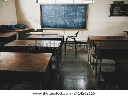 Indian classroom with wooden desks and blackboard on the wall. Royalty-Free Stock Photo #2414262115
