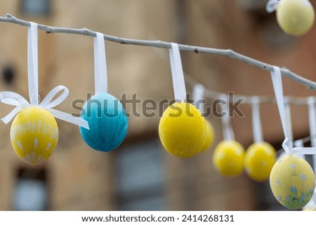 Colorful handmade egges for easter in branches outdoor. Decorating trees with hanging eastereggs in city street. Tradition holiday on christianity religion. Symbol of resurrection to new life. Royalty-Free Stock Photo #2414268131