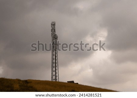 Communication tower in field with dark storm clouds in the background