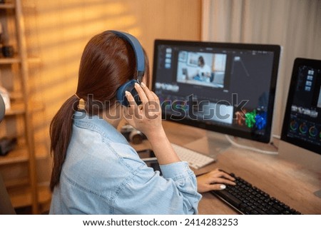 Woman editor working with footage on computer screens at desk Royalty-Free Stock Photo #2414283253