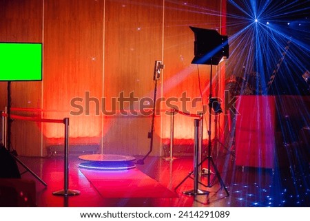 360-degree spinner photo booth setup with colorful laser lights, a green screen, and a camera on a tripod. Royalty-Free Stock Photo #2414291089