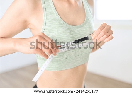 A woman measuring her chest circumference with a measuring tape Royalty-Free Stock Photo #2414293199