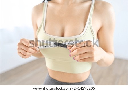A woman measuring her chest circumference with a measuring tape Royalty-Free Stock Photo #2414293205