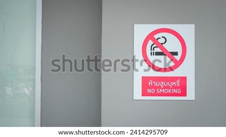 "No smoking" sign with red circle icon (Thai and English text) that showed on the building part. Sign and symbol for healthcare, selective focus.
