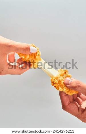 Crispy cheese fried breaded mozzarella cheese sticks stretch two hands Royalty-Free Stock Photo #2414296211
