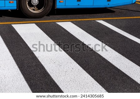 Crosswalk on asphalt road with bus in background, city scene