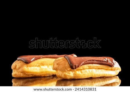 Two delicious chocolate eclairs, close-up isolated on a black background. Royalty-Free Stock Photo #2414310831