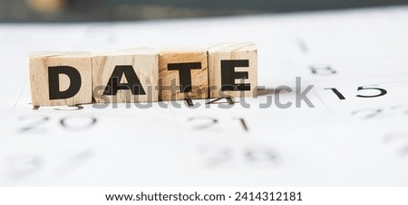 DATE - a word made of wooden blocks with black letters, a row of block is located on left side calendar paper. deadline, time schedule photo concept.