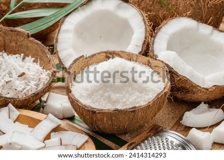 Fresh opened coconuts along with coconut slices, flakes and coconut leaves on a wooden table. Nice fruit background for your projects.  Royalty-Free Stock Photo #2414314293