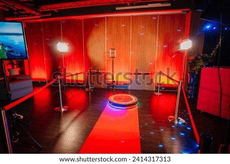 360 spinner photo booth setup with a red carpet and lighting in a venue with red ambient lighting.