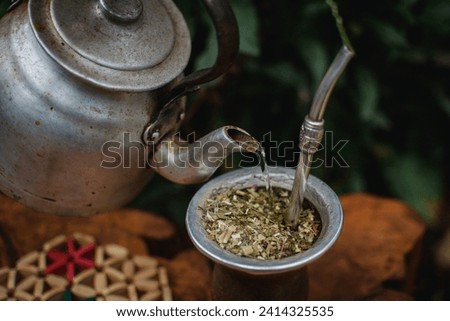 Brewing mate, steel kettle and traditional Argentine porongo mate, enjoying a good traditional Argentine mate in nature outdoors. Royalty-Free Stock Photo #2414325535