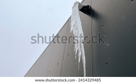 icicles on a pipe in the wall of a building, condensation, melting in winter.