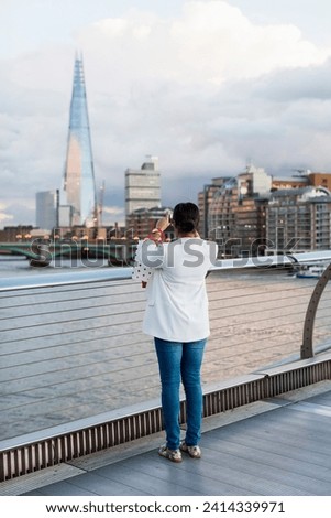 Uk- london- woman standing on a bridge taking picture of the shard