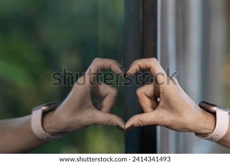 Chinese girl raises her hands and makes heart sign express meaning love friendship and kindness for her friends and lovers. Chinese girl uses her hands make heart shaped sign means love and friendship