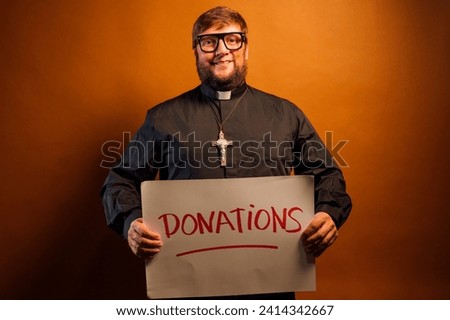 Portrait of a priest with crucifix and black shirt asking for money donations for the church with a sign.