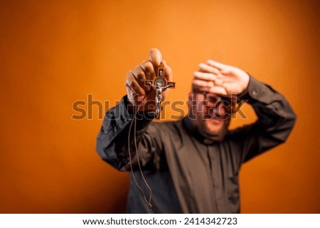 Portrait of an exorcist priest with crucifix and black shirt. Royalty-Free Stock Photo #2414342723