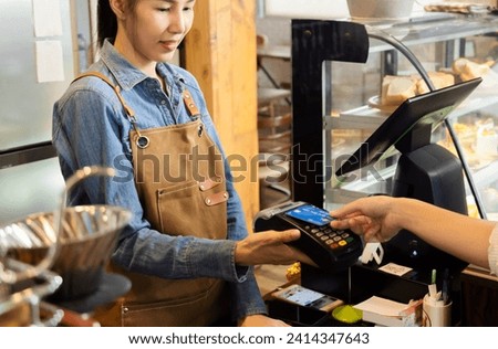 Closeup waitress hand holding credit card swipe on wireless digital payment machine, worker wearing apron working in cafe retail small business using modern cashless touchless payment transaction