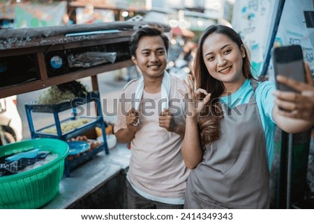 indonesian seller couple taking picture behind traditional food cart