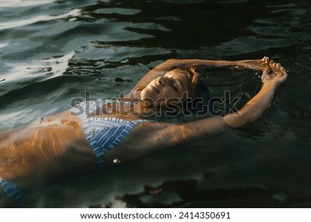 Portrait of woman floating in a lake Royalty-Free Stock Photo #2414350691