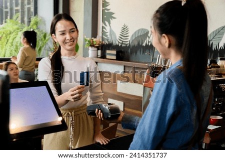 Asian waitress barista worker accepts credit card cashless payments from customer female in cafe restaurant, happy woman open bakery coffee shop, small business entrepreneur start-up lifestyle 
