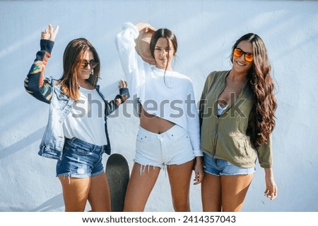 Group picture of three friends standing in front of a wall