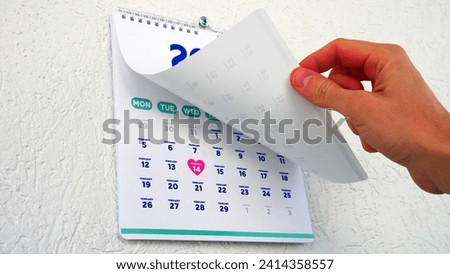 A male hand flipping a January page of the wall calendar 2024 showing the upcoming St Valentine's Day date on the next one