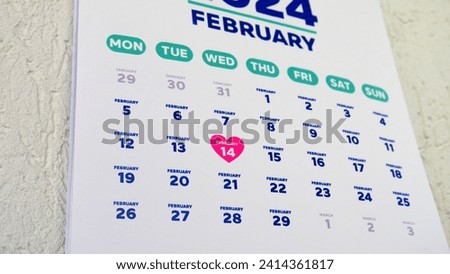 Close-up of St Valentine's Day date marking with a pink heart shape symbol on the wall calendar February page 2024