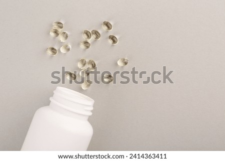 Bottle and vitamin capsules on light grey background, top view. Space for text