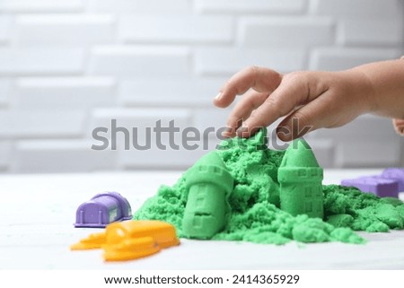 Little child playing with green kinetic sand at white table, closeup. Space for text Royalty-Free Stock Photo #2414365929