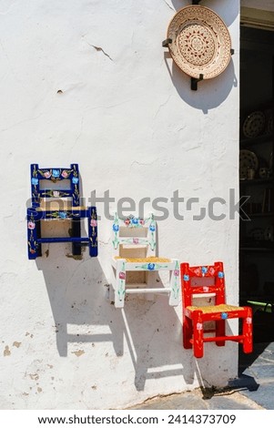 Three traditional Portuguese chairs on the white wall. Vertical image.