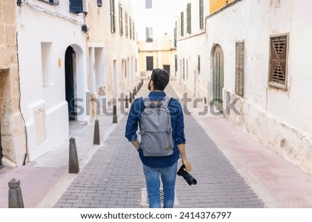 Back view of man with camera exploring the city- mao- menorca- spain Royalty-Free Stock Photo #2414376797
